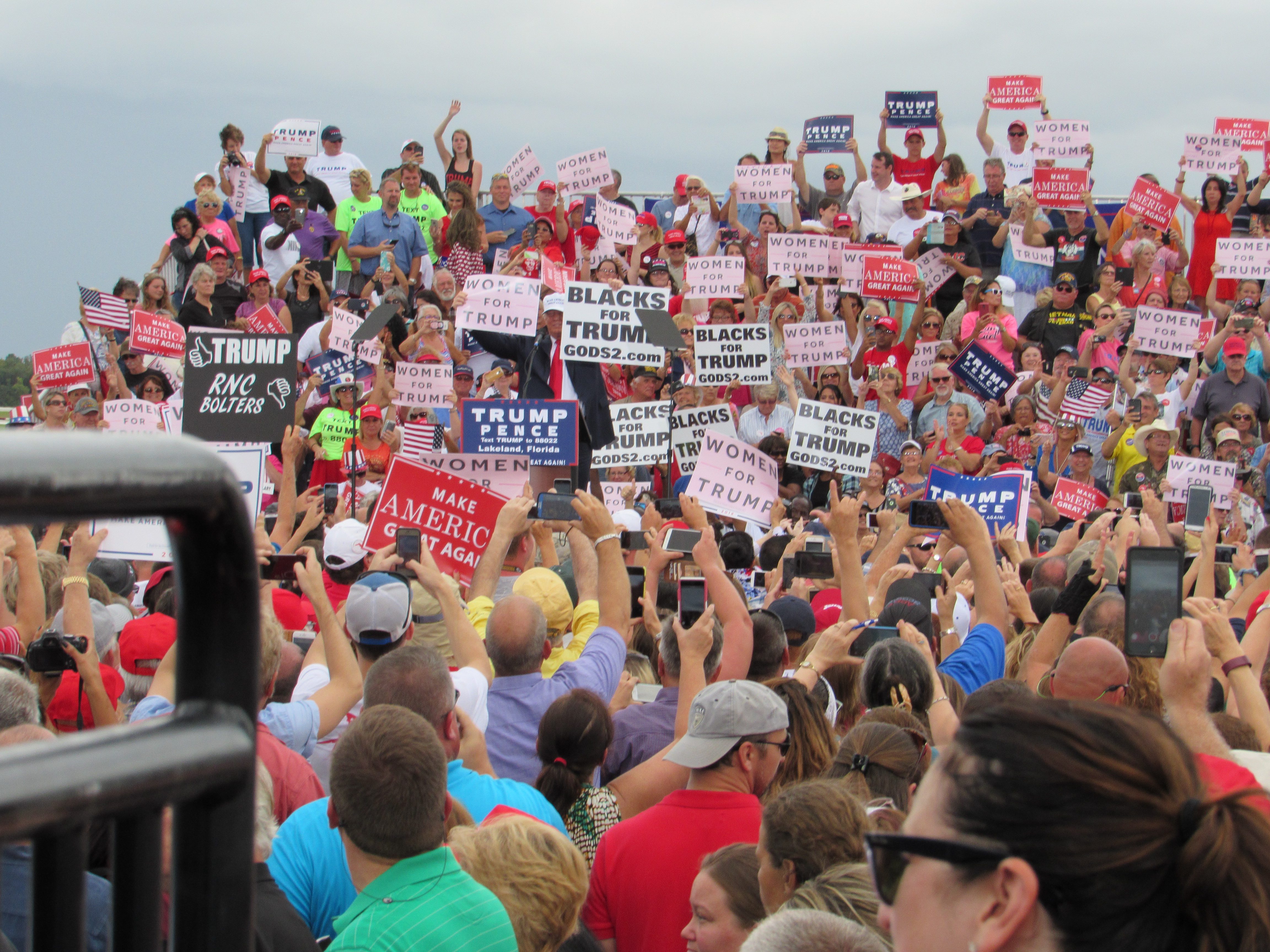 Trump holds Women for Trump and Blacks for Trump signs at end of Lakeland, FL rally Oct 12, 2016