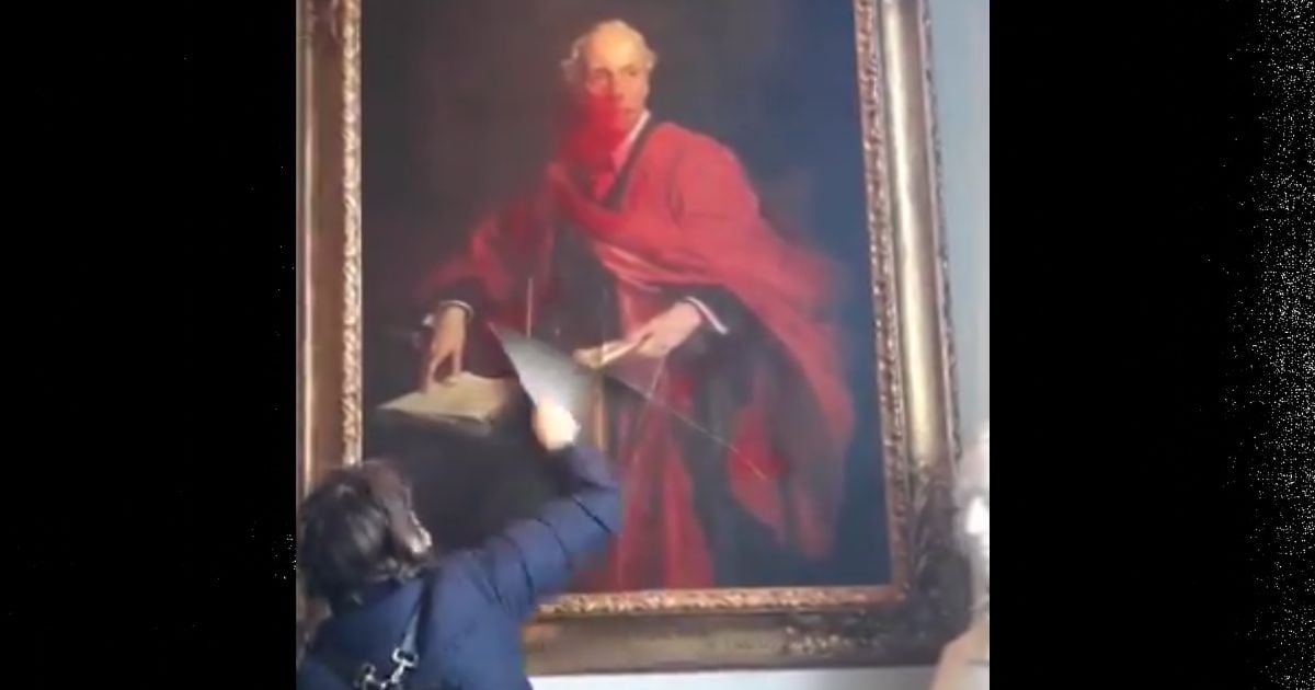 După ce a pulverizat cu vopsea roșie portretul, protestatarul a �nceput apoi să-l taie.