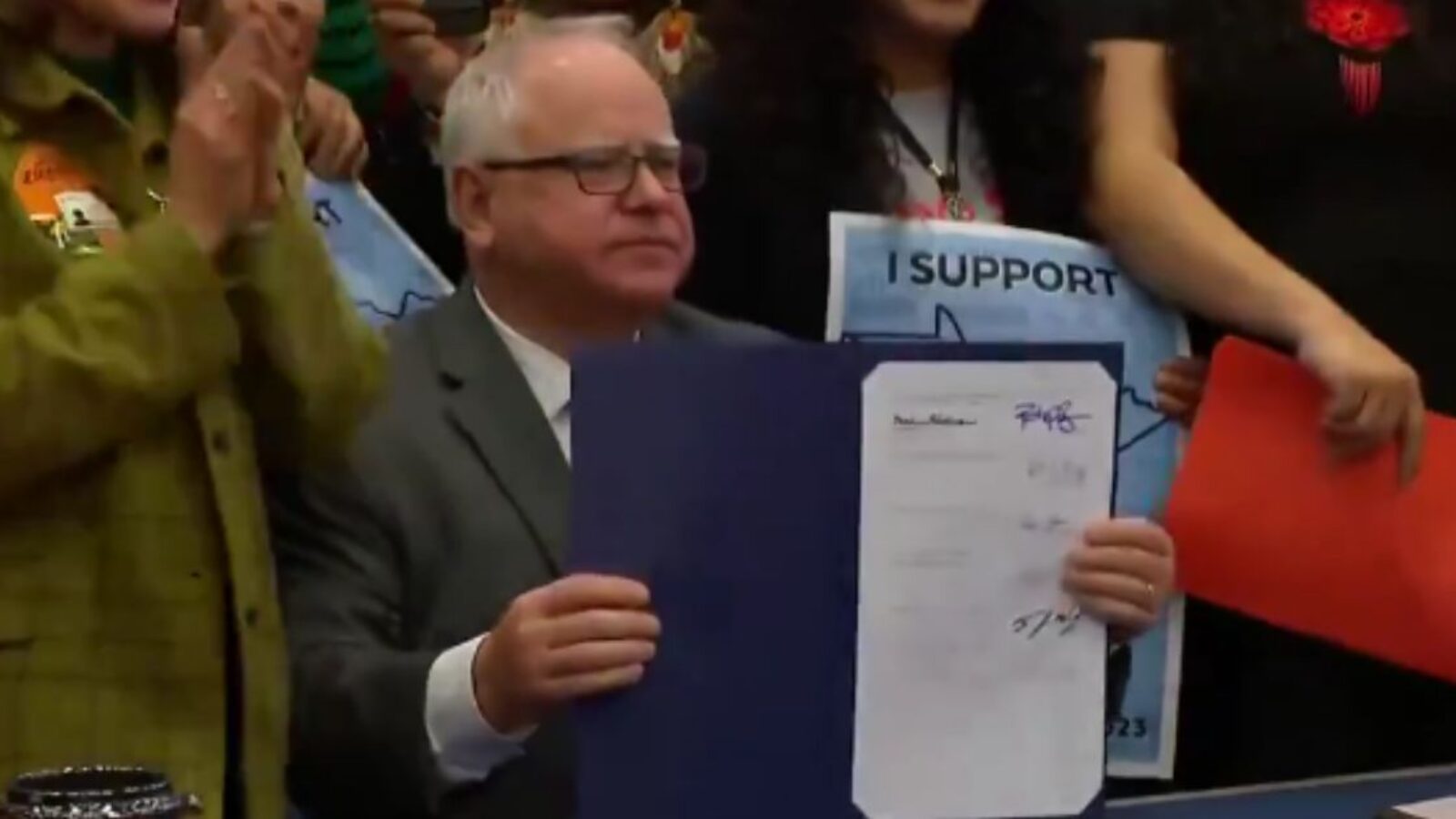 Minnesota Gov. Tim Walz holds up a bill he signed that will allow anyone in the state to receive their driver’s license, regardless of their immigration status.