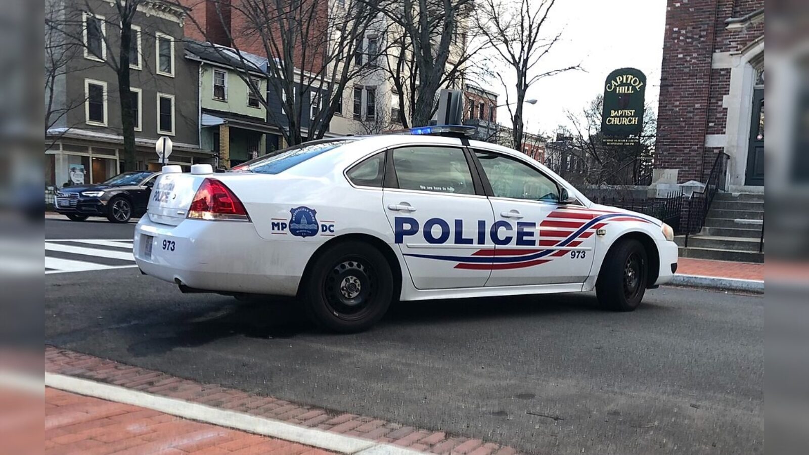 DC police car parked on a city street near Capitol Hill Baptist Church, showcasing the vehicle's distinct markings and emergency lights.