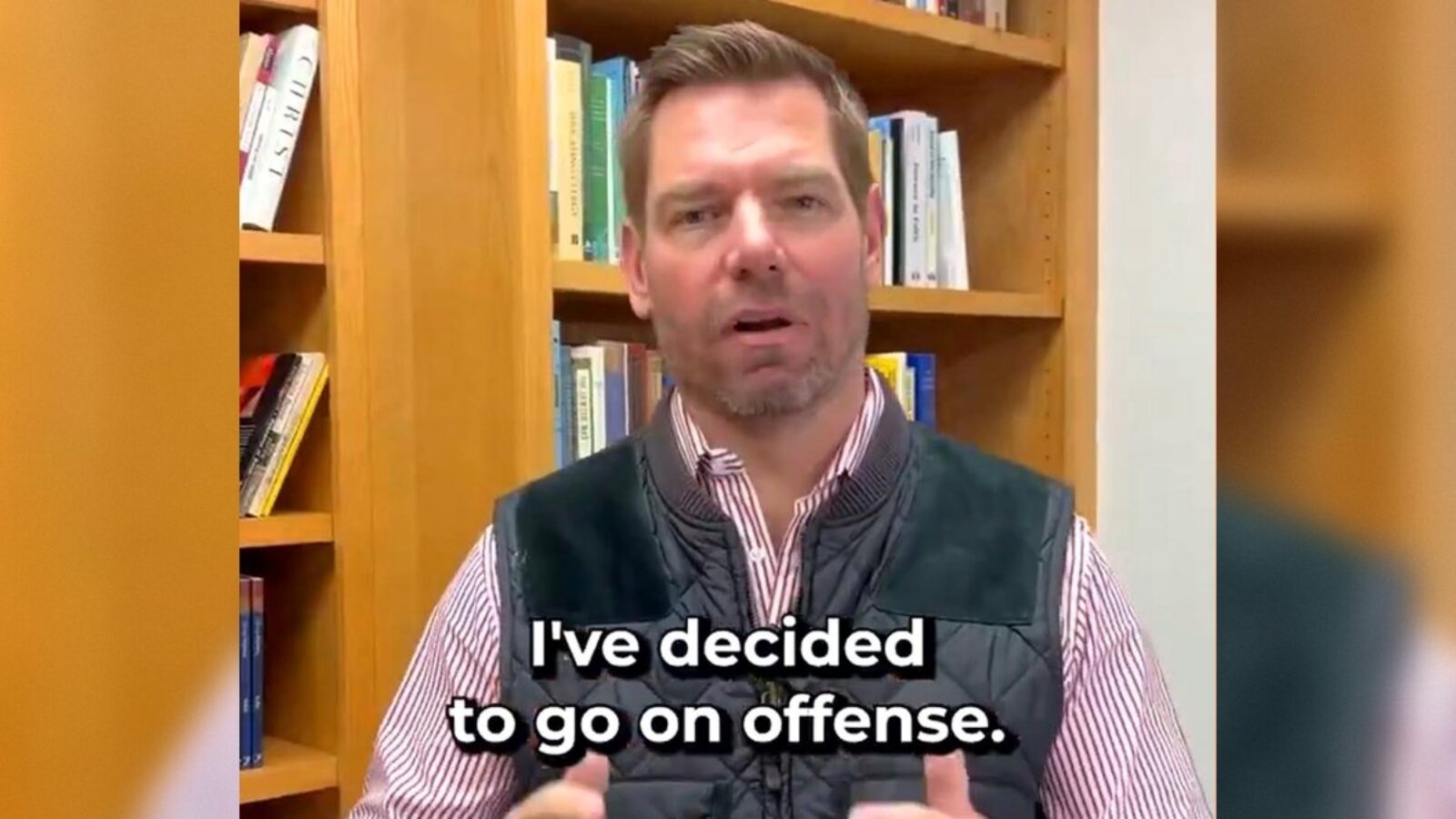 Person speaking in front of a bookshelf, discussing a strategic decision to take action in a professional context.