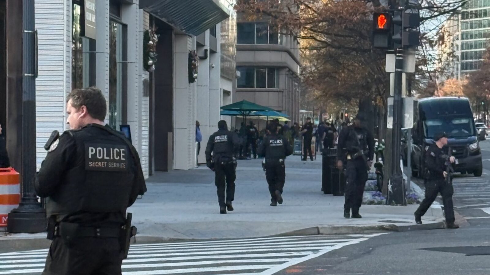 Police and Secret Service officers patrol a busy urban street, ensuring security and safety in the area.