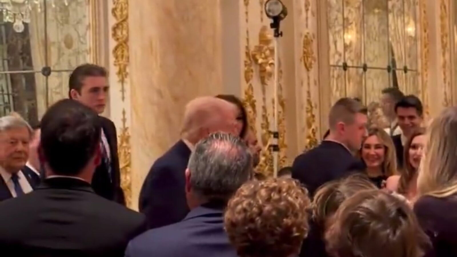 Donald Trump mingles with guests at a formal event in an opulent venue, showcasing elegant decor and a lively atmosphere.