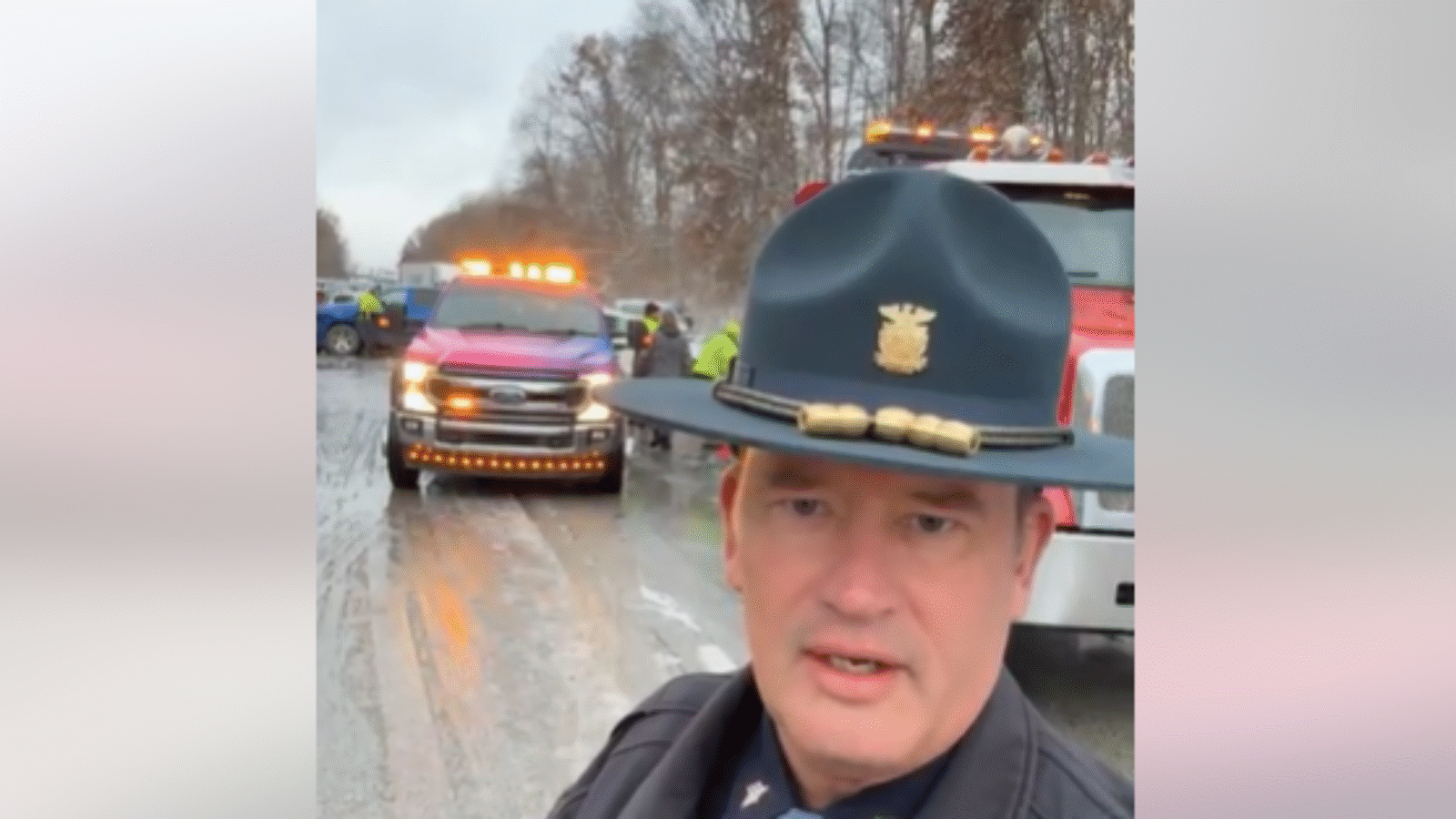 Police officer addressing an accident scene with emergency vehicles on a wet road, highlighting the importance of safety and traffic management.