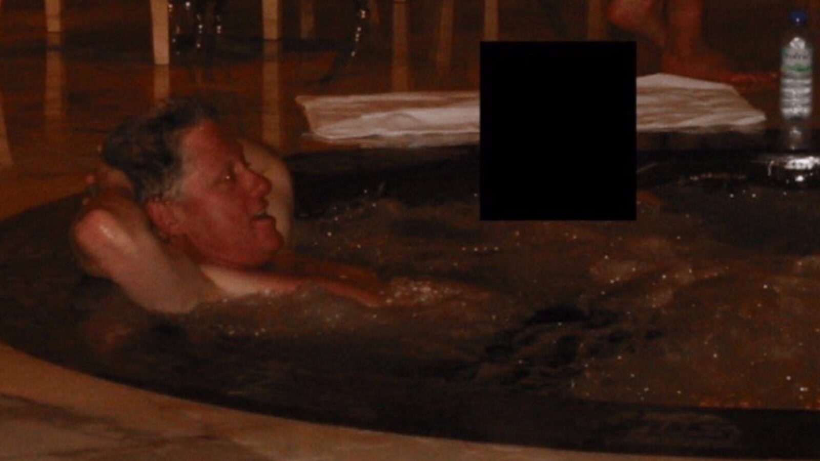 Man relaxing in a hot tub with a serene expression, surrounded by a tranquil indoor setting.