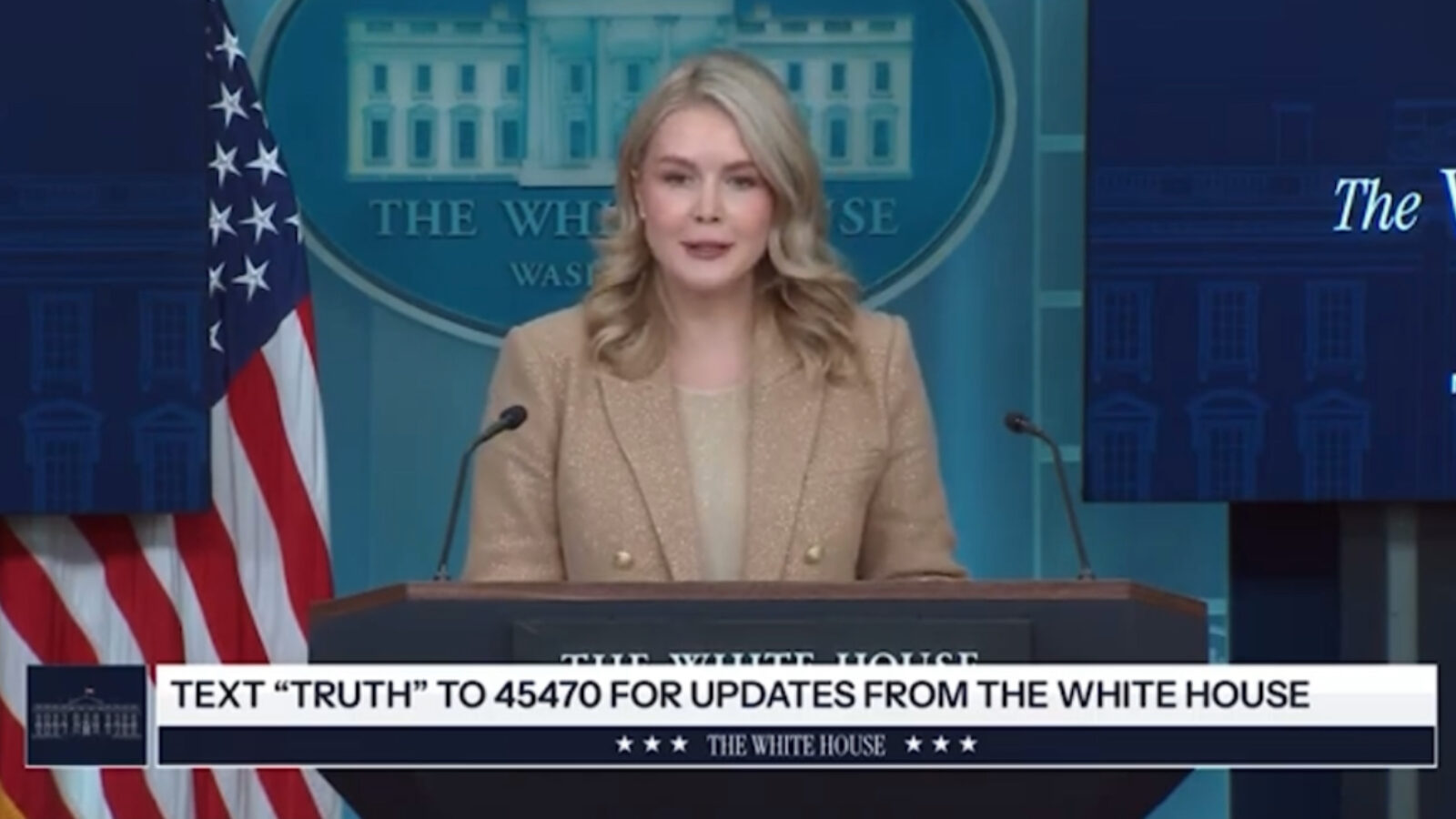 Press briefing at the White House featuring a speaker discussing updates and encouraging text subscriptions for information.