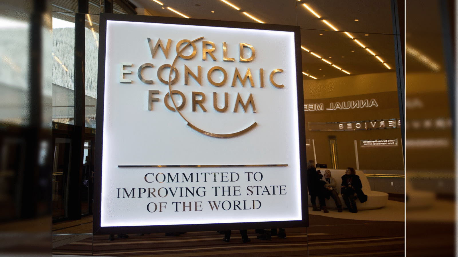 Signage of the World Economic Forum highlighting its commitment to improving global conditions, displayed prominently at the annual meeting venue.