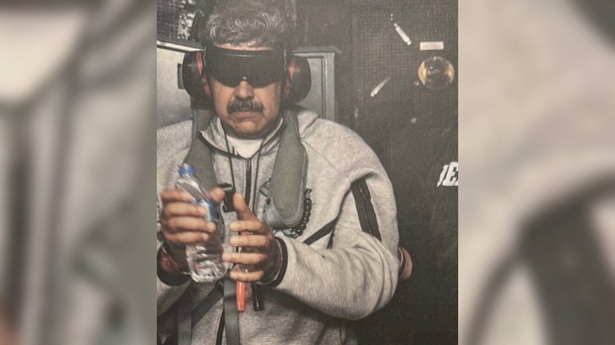 Person wearing protective eyewear and headphones holds a water bottle while engaged in a specialized activity, showcasing safety measures in a controlled environment.