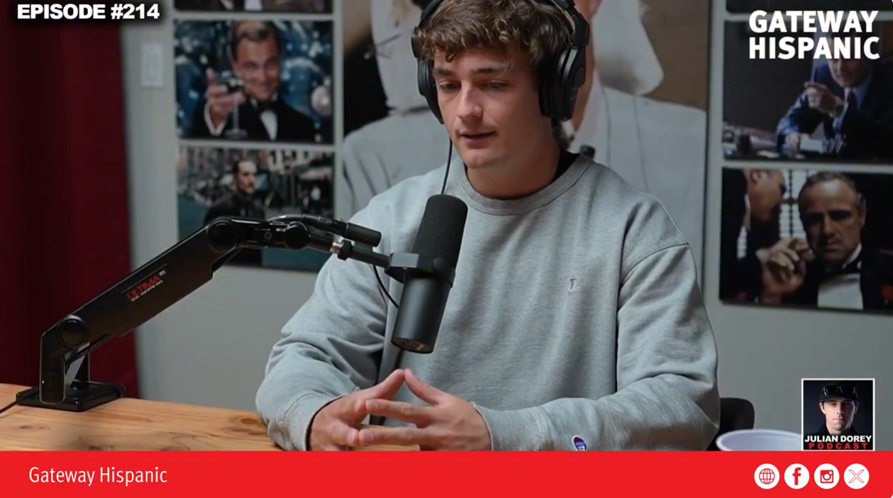 Podcast host Julian Dorey discusses various topics in episode 214 of Gateway Hispanic, featuring a modern studio setup and engaging visuals in the background.
