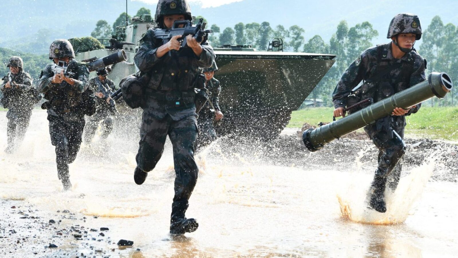 Soldiers in tactical gear sprint through water during a military training exercise, showcasing teamwork and readiness for combat scenarios.
