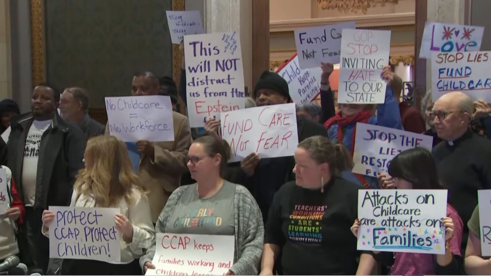 Protesters rally for childcare funding and support, holding signs with messages advocating for children's welfare and criticizing political actions affecting families.