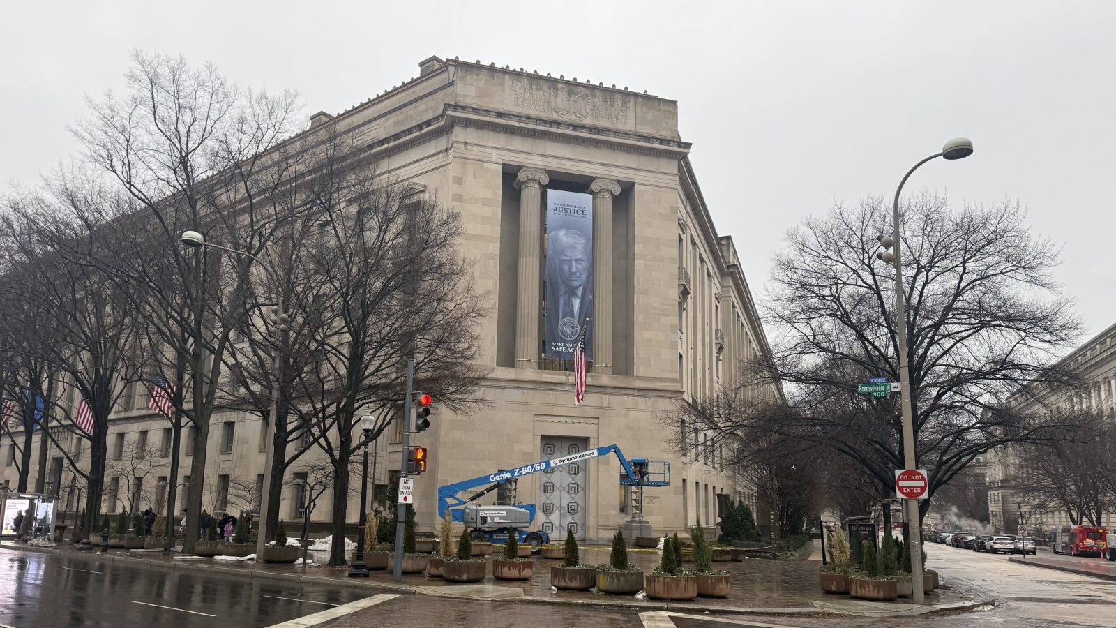 U.S. Department of Justice building featuring a large banner and construction equipment on a rainy day in Washington, D.C.