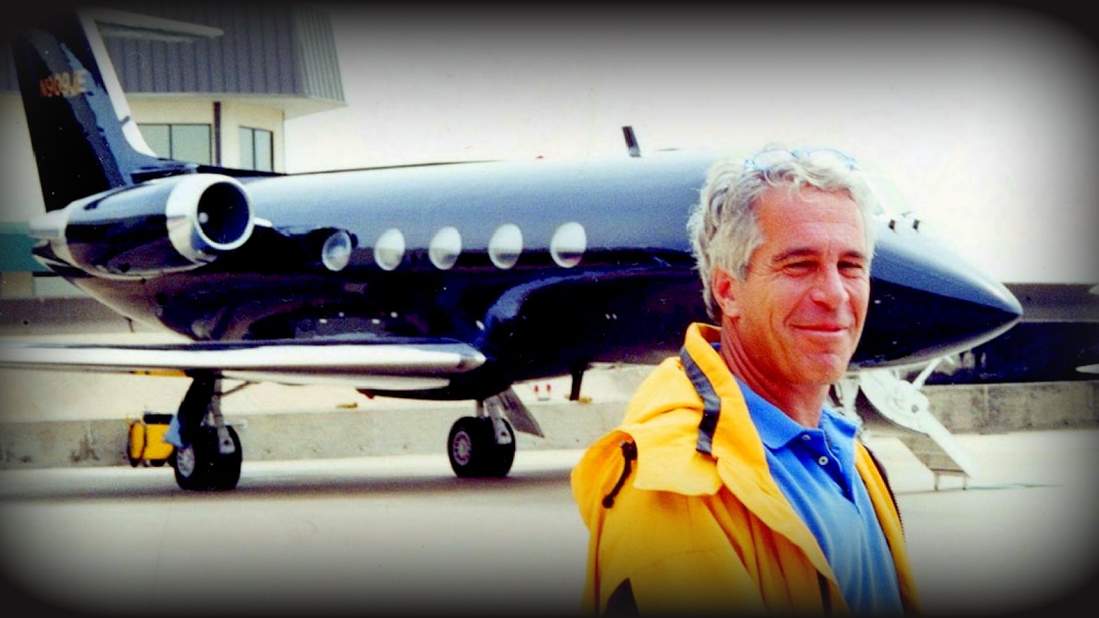 Man in a yellow jacket stands in front of a black private jet at an airport, showcasing aviation and luxury travel.