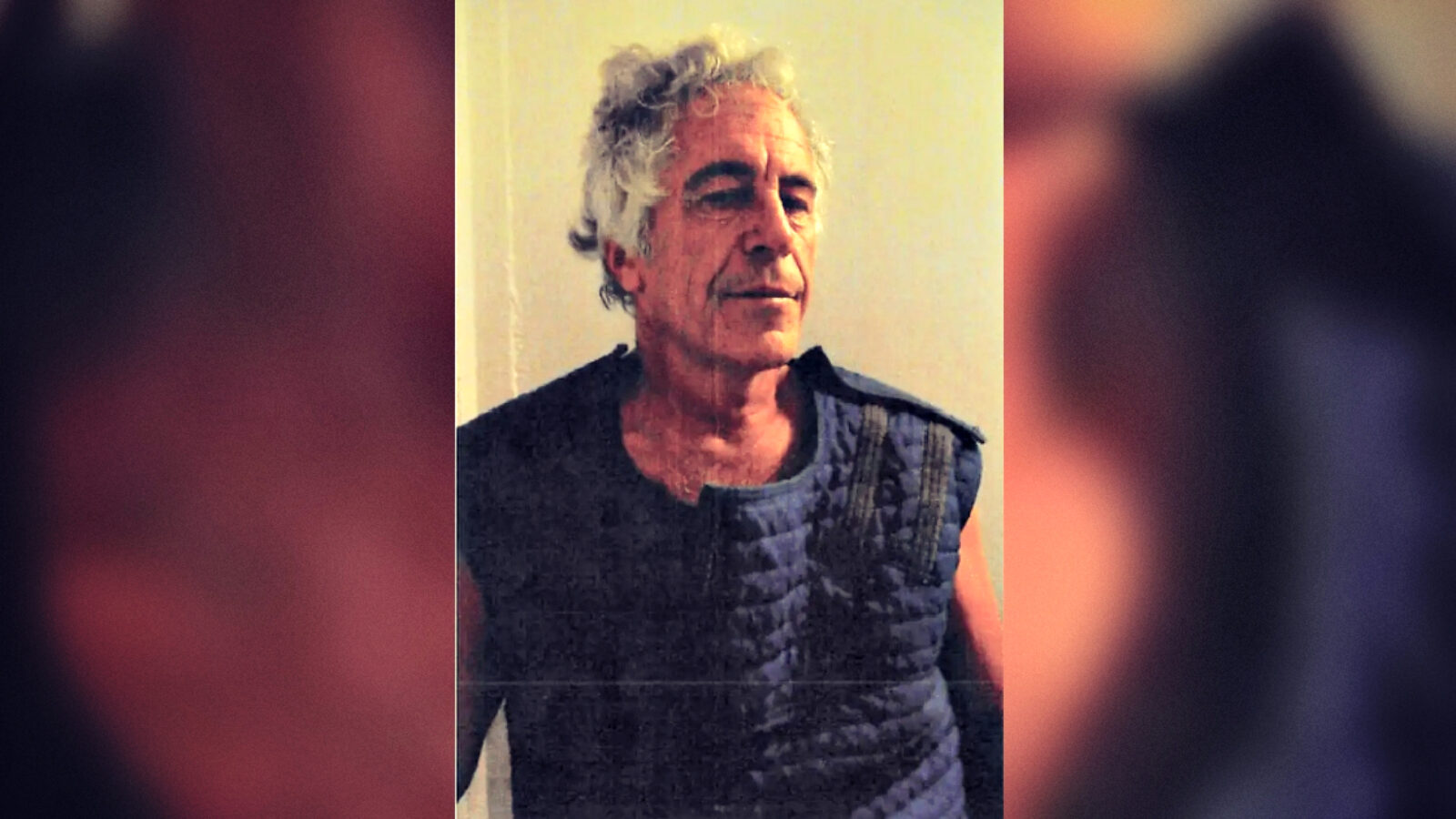 Image of a man wearing a dark vest, with gray hair, appearing contemplative against a neutral background.