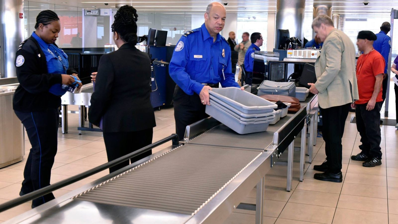 Transportation Security Administration officers assist travelers during security screening at an airport checkpoint, ensuring safety and compliance with regulations.