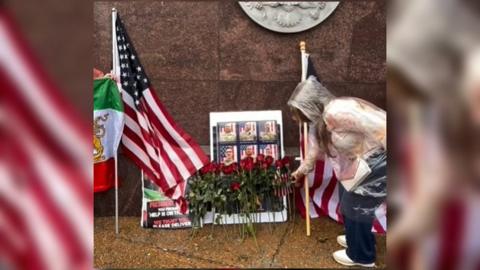 A woman in a raincoat places roses at a memorial adorned with American and Mexican flags, honoring fallen heroes.