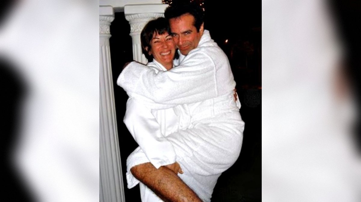 Couple in white bathrobes sharing a joyful moment, with one partner playfully lifting the other, set against a softly lit background.