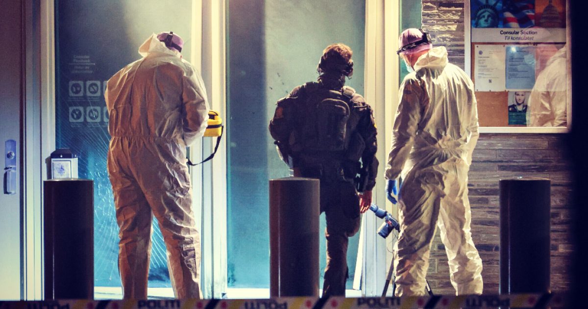 Emergency responders in protective gear investigate a building entrance, highlighting safety measures during a potential hazardous situation.