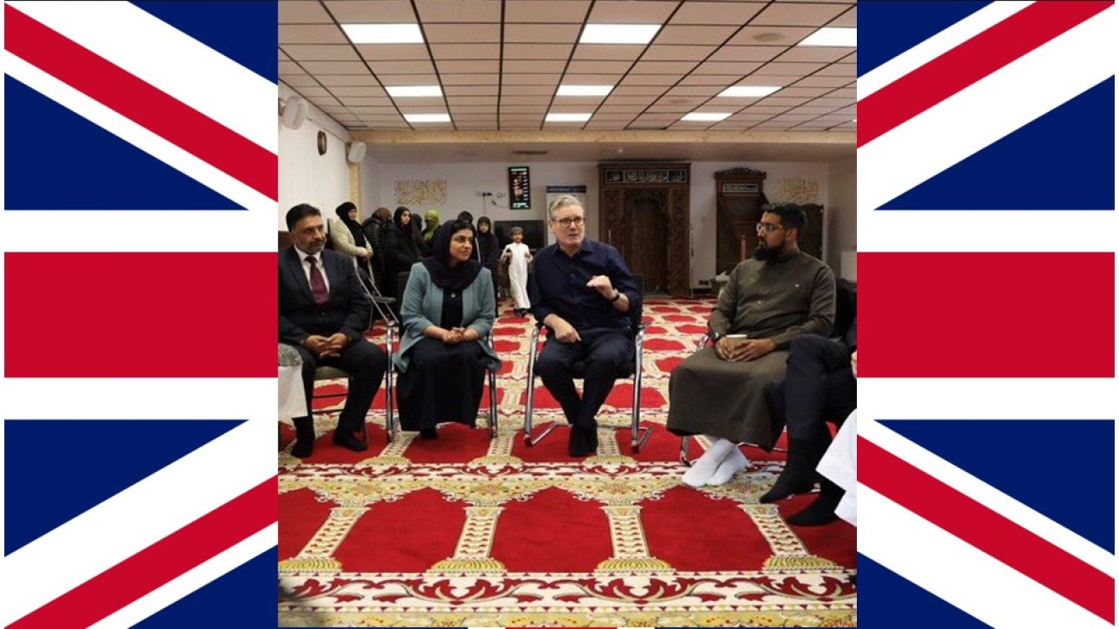 A diverse group of individuals engaged in discussion in a mosque setting, with traditional decor and a vibrant carpet.