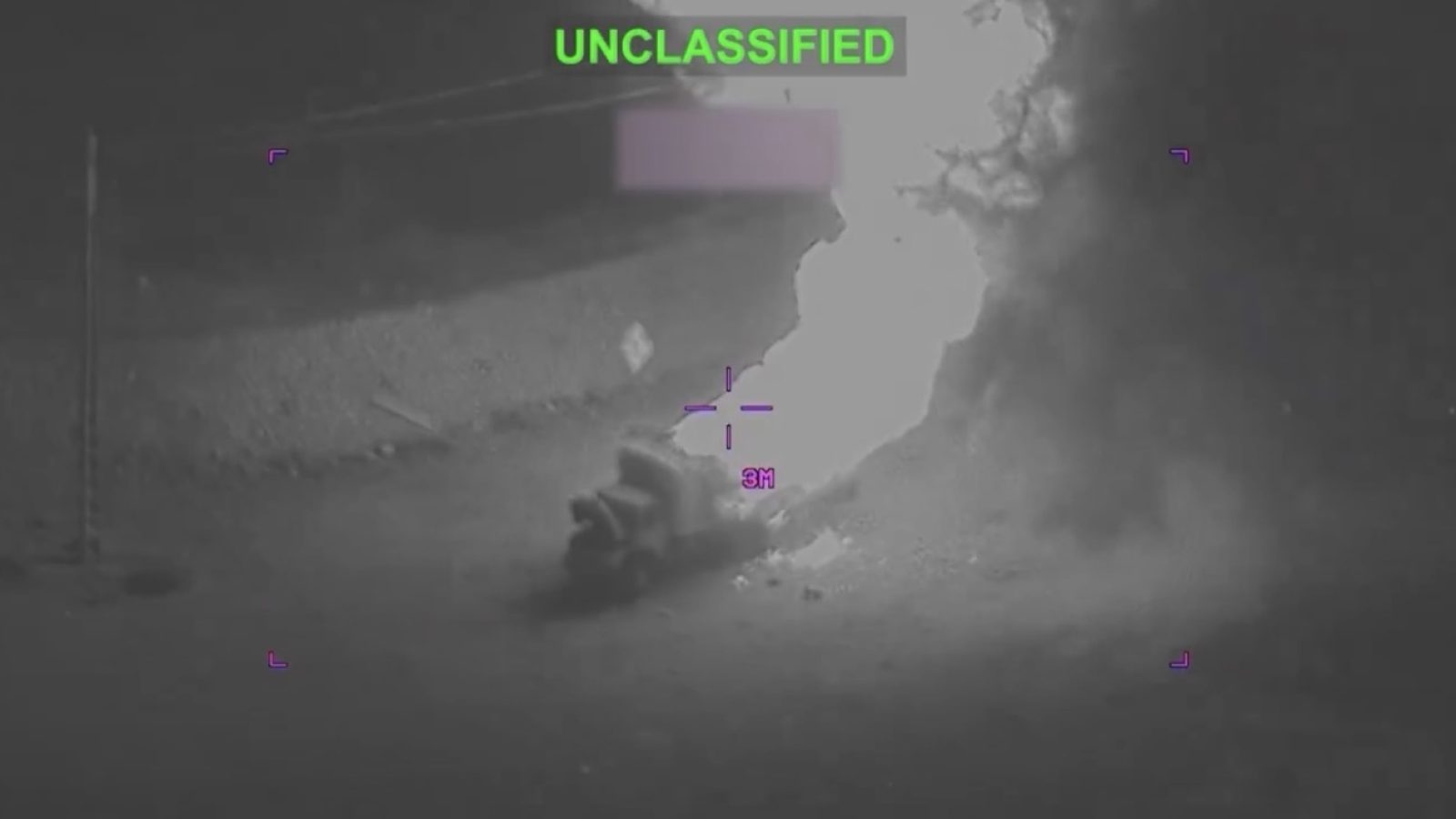 Night vision image showing a vehicle engulfed in flames, with an unclassified overlay and targeting reticle indicating distance.