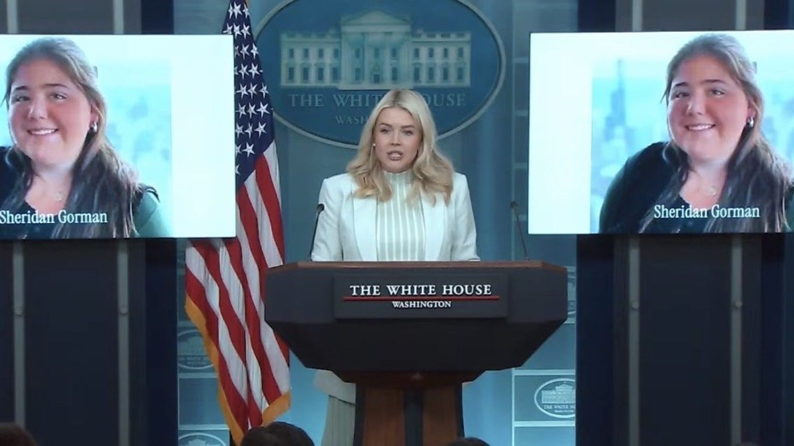 Press briefing at the White House featuring Sheridan Gorman speaking at the podium with a backdrop displaying her image.