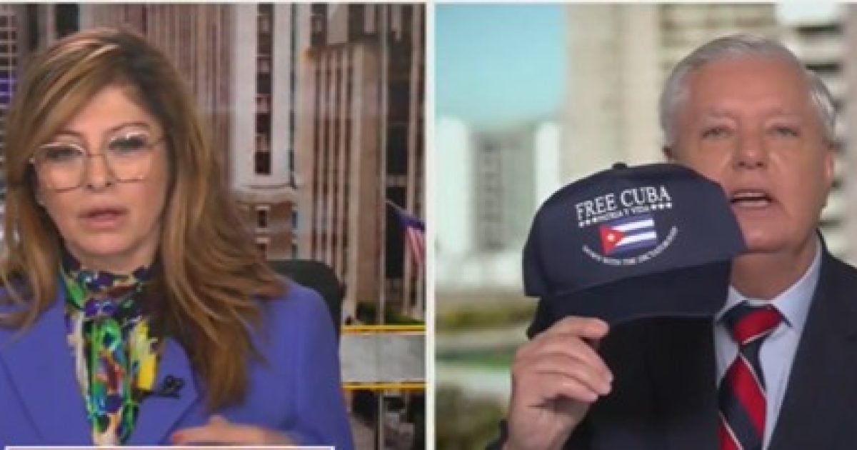 News segment featuring a woman in a blue blazer and glasses alongside a man holding a "Free Cuba" hat, discussing political issues related to Cuba.