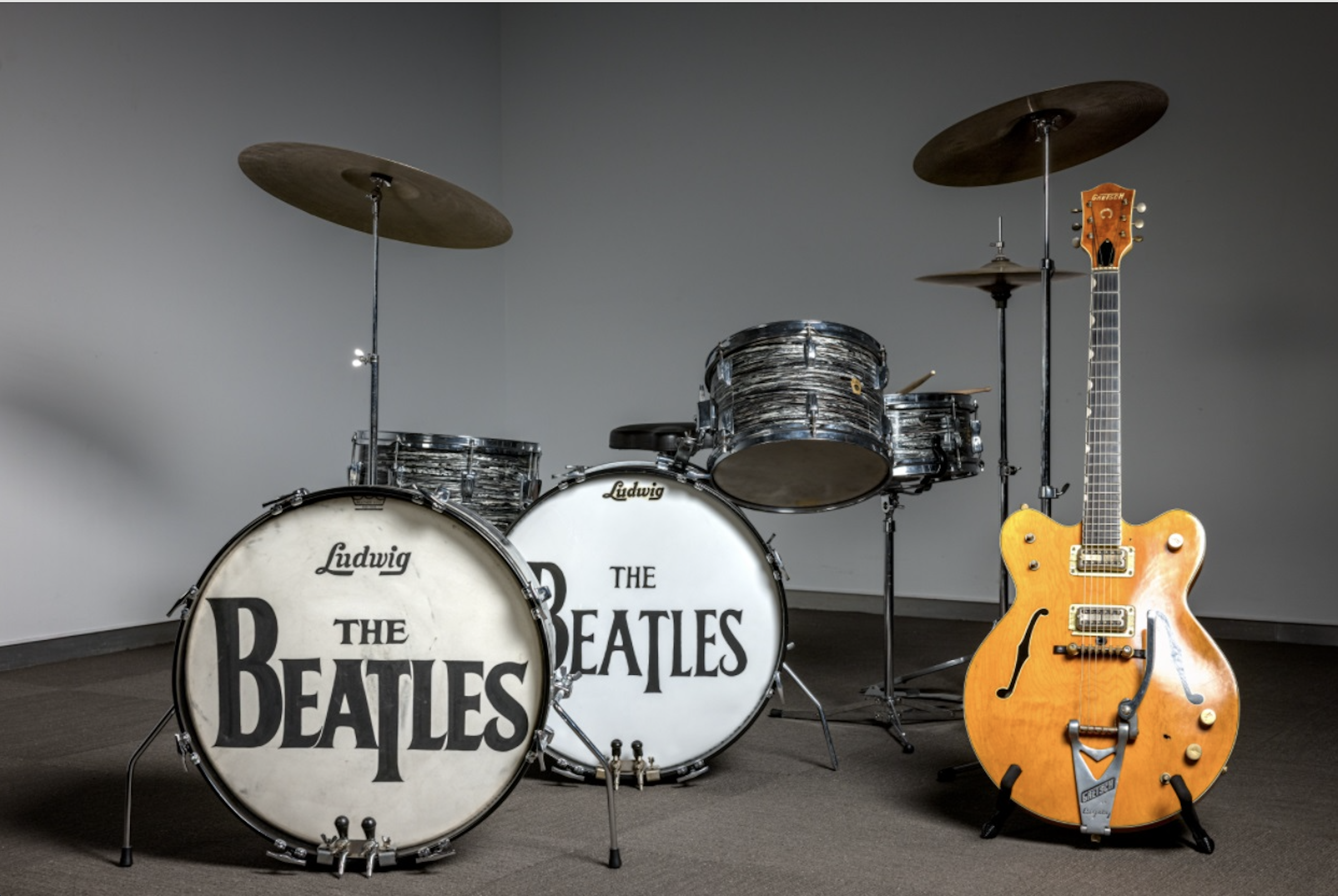 Beatles-themed Ludwig drum set and Gretsch guitar displayed in a modern setting, showcasing iconic music memorabilia.