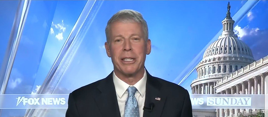 Television host speaking on Fox News Sunday with the U.S. Capitol building in the background, highlighting current political discussions.