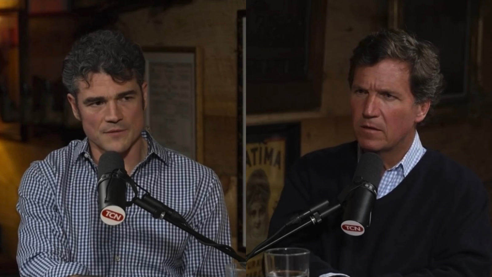 Two men engaged in a serious discussion at a podcast studio, with microphones and glasses of water visible.
