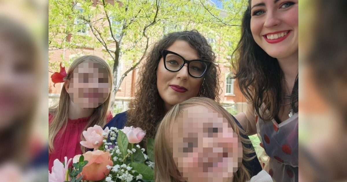 Group of smiling women and children holding a bouquet of flowers outdoors, surrounded by green trees and a sunny atmosphere.