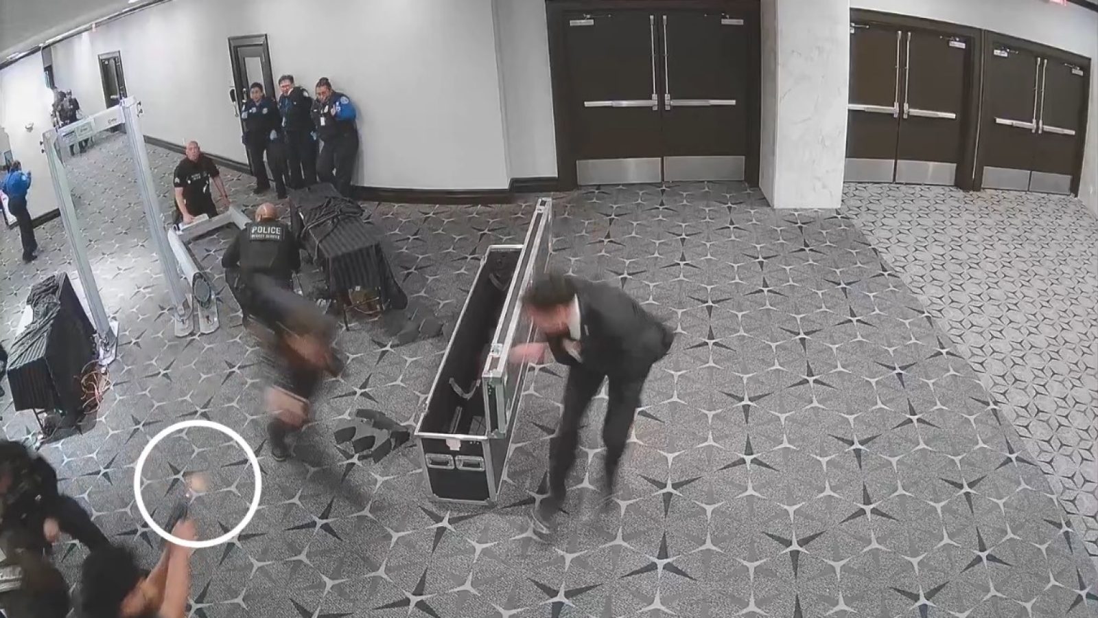 Security footage captures a chaotic scene with multiple individuals, including police officers, in a corridor during an incident on April 25, 2026.