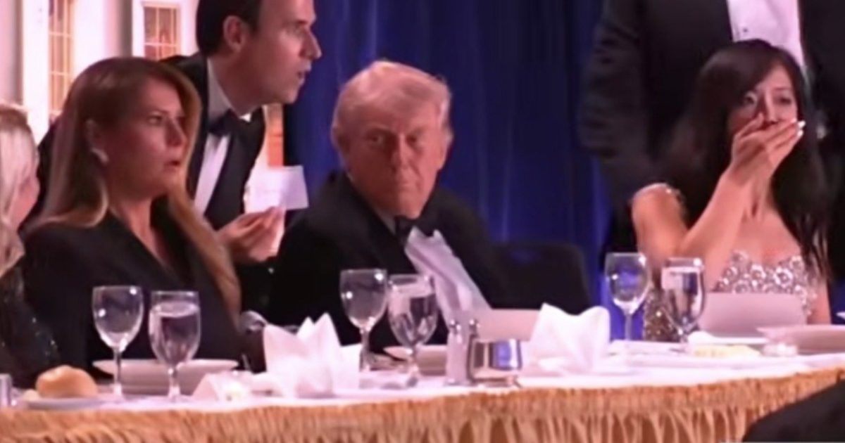 Former President Donald Trump seated at a formal dinner, surrounded by guests in elegant attire, with a tense atmosphere evident among the attendees.