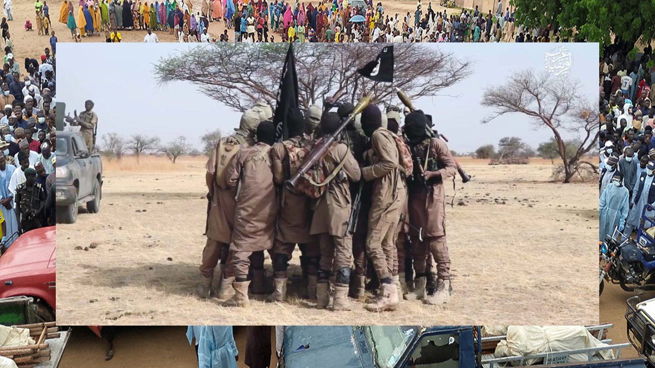 A group of armed militants in tactical gear gathered in a barren landscape, showcasing their weapons and flags.