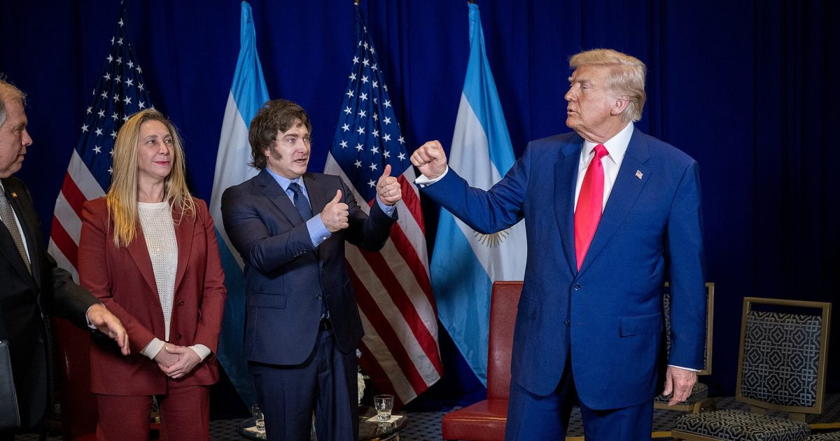 Former President Donald Trump interacts with Argentine officials, showcasing flags of the United States and Argentina in a diplomatic setting.