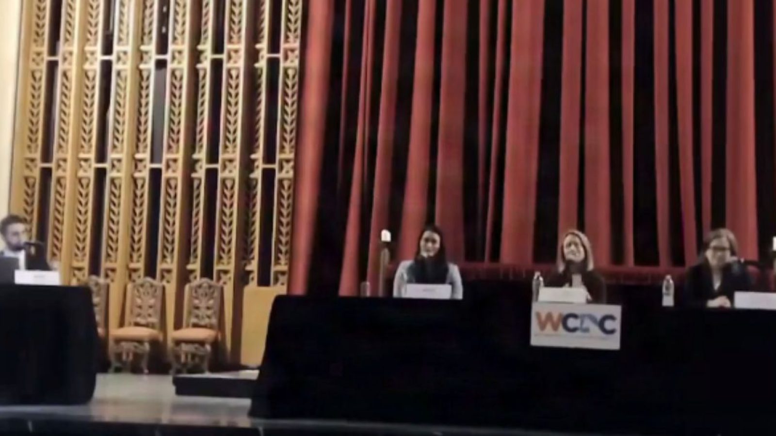 Panel discussion featuring four speakers at a conference, with a focus on community engagement and collaboration, set against a decorative backdrop.