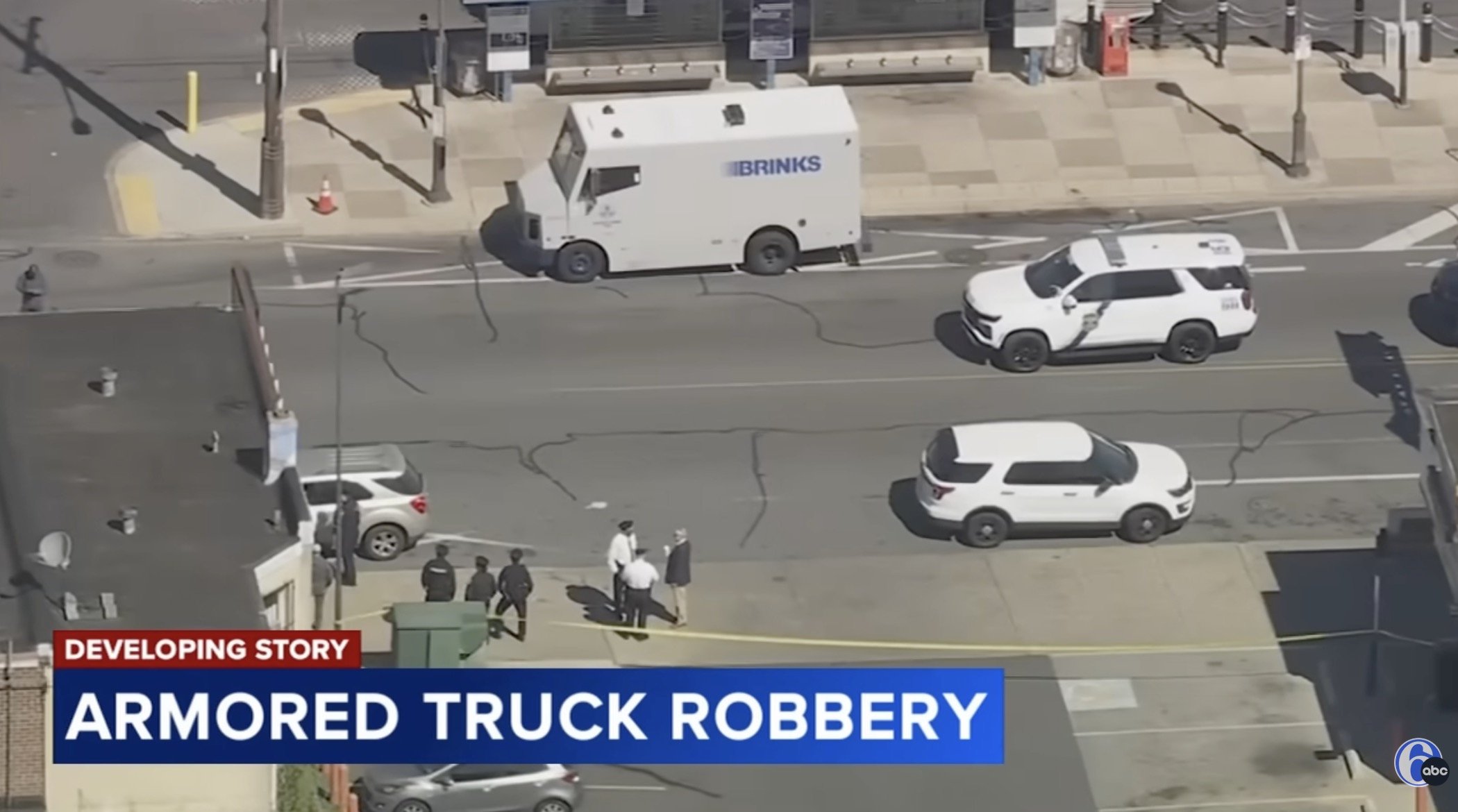 Aerial view of an armored truck robbery scene with police presence and vehicles on a city street.