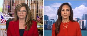 Two women in professional attire discussing finance, with a cityscape background featuring skyscrapers and American flags.