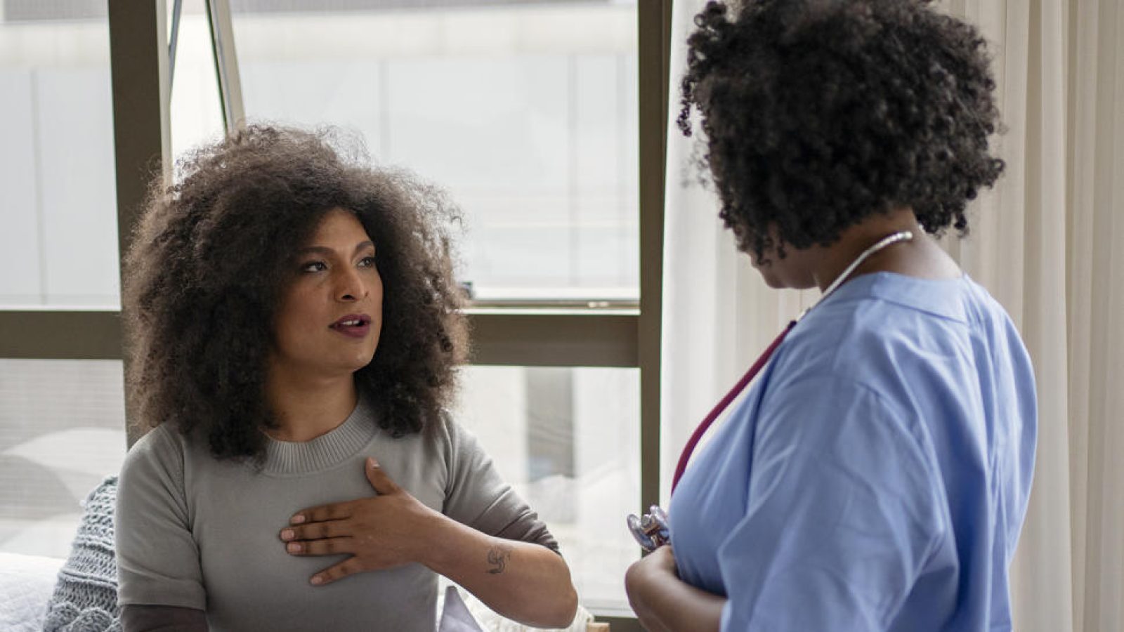 A patient discusses symptoms with a healthcare professional in a bright, modern medical setting.