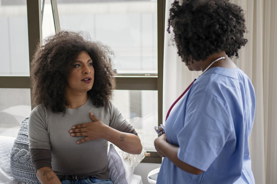 A patient discusses symptoms with a healthcare professional in a bright, modern medical setting.