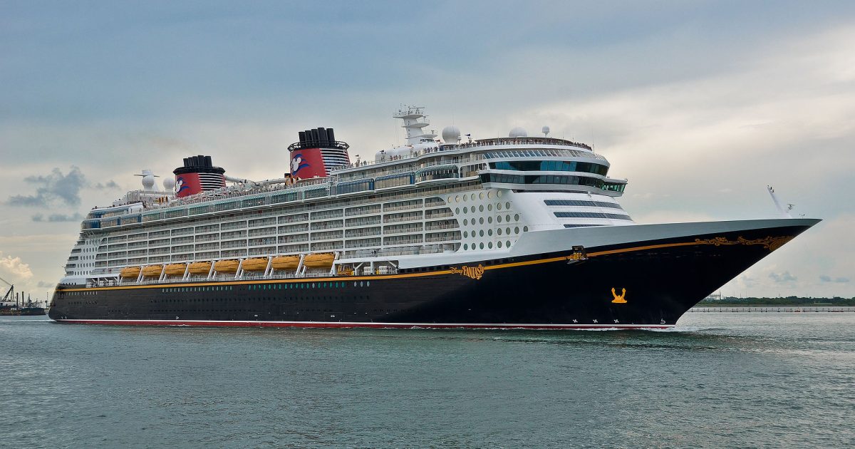 Disney Fantasy cruise ship sailing in calm waters with a cloudy sky in the background.