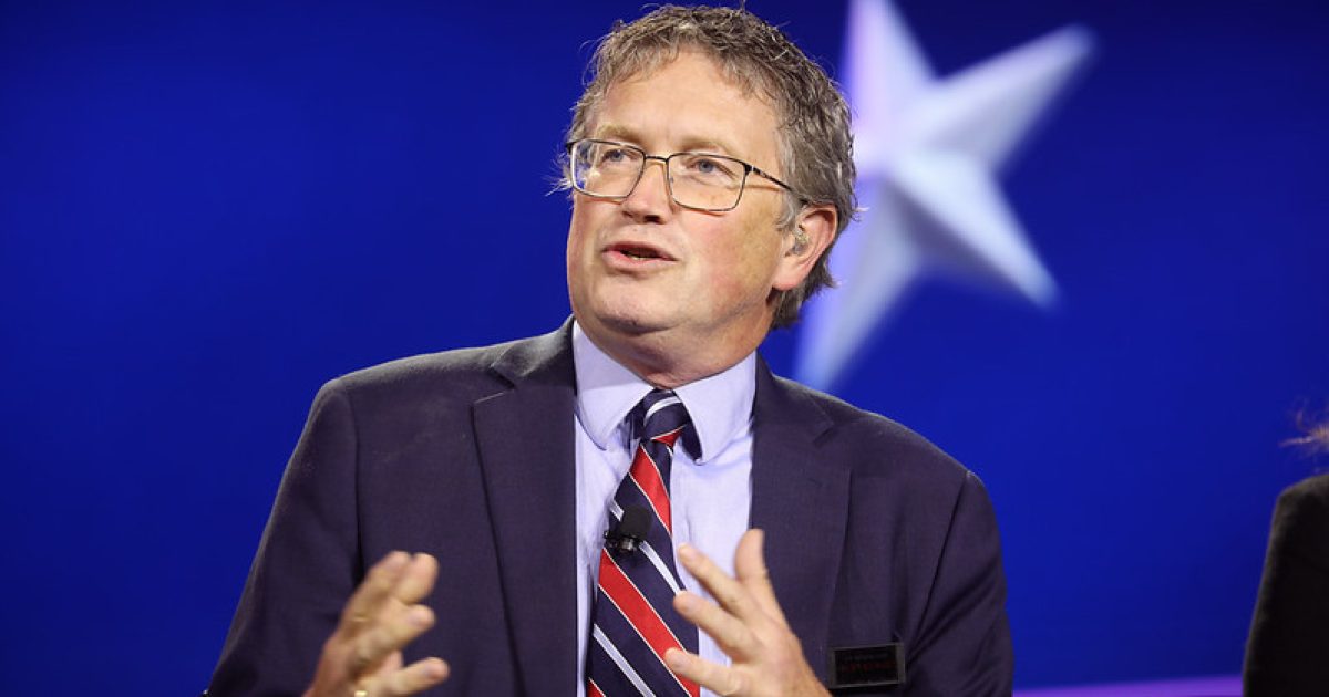 Man in a suit speaking at a panel discussion, with a blue background featuring a star, conveying engagement and expertise.
