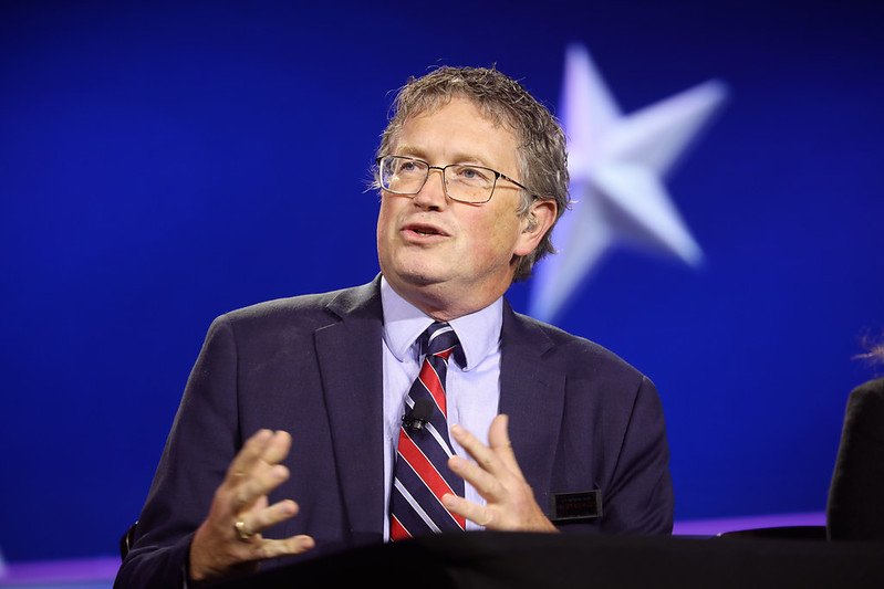 Man in a suit speaking at a panel discussion, with a blue background featuring a star, conveying engagement and expertise.