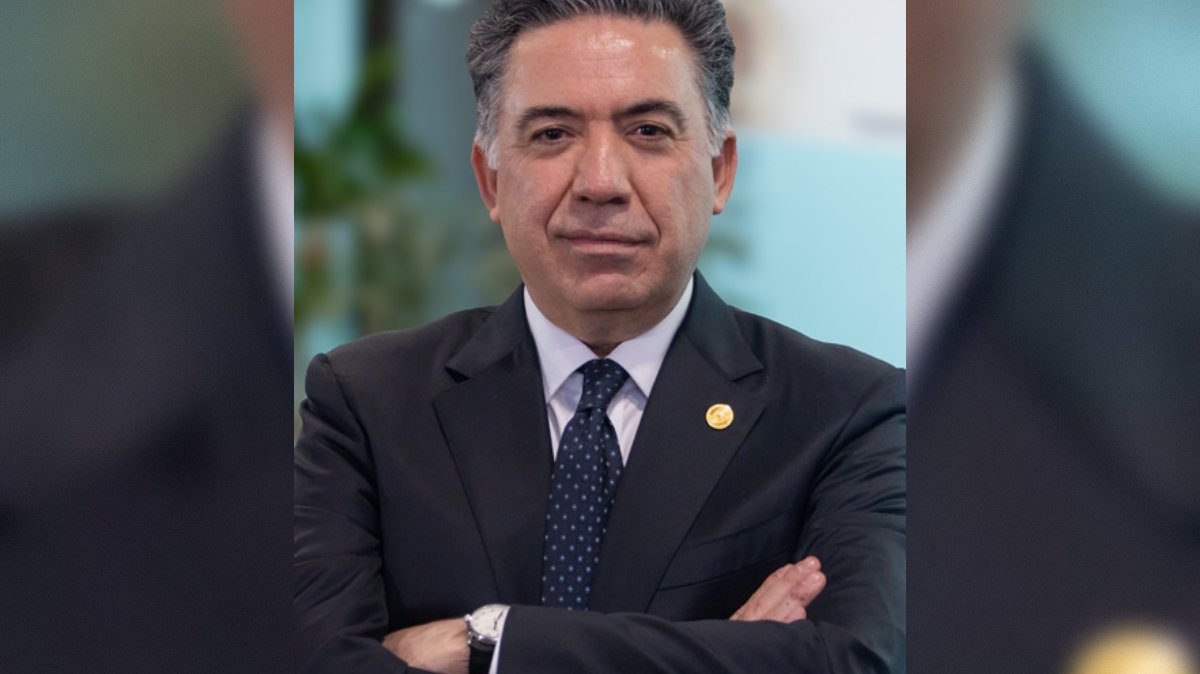 Business professional in a suit with arms crossed, showcasing confidence and leadership in a modern office environment.