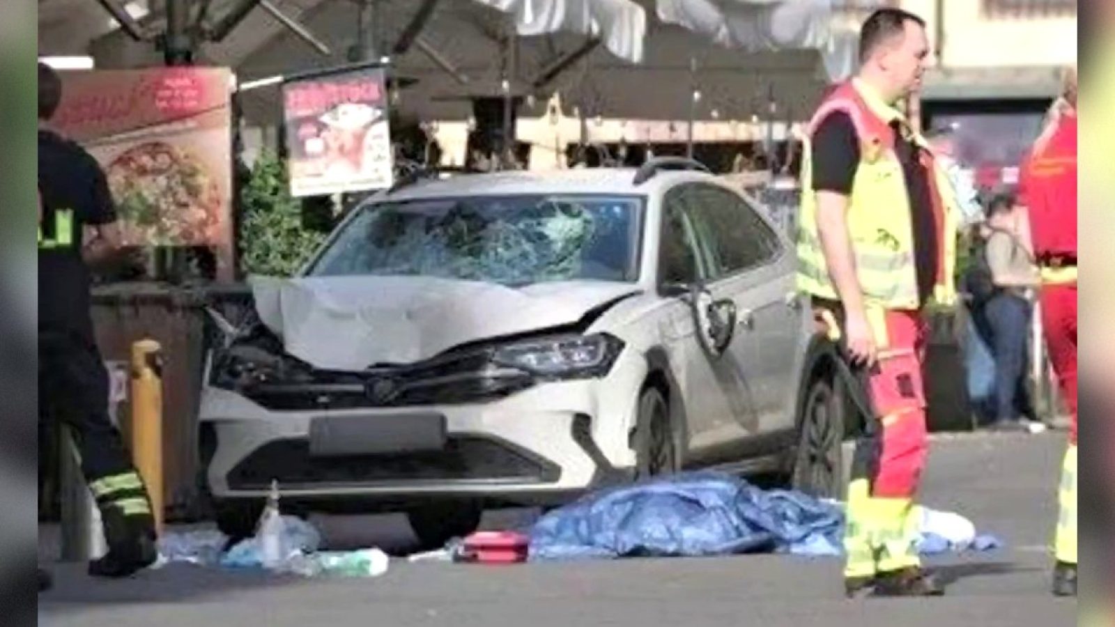 Emergency responders at the scene of a serious accident involving a damaged car and debris on the ground.