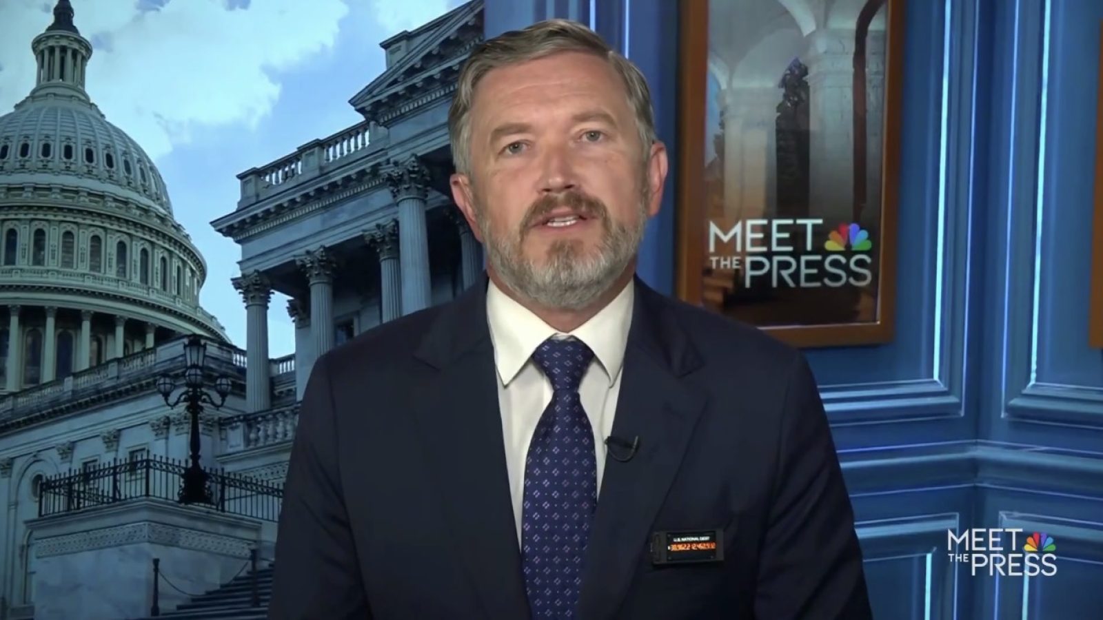 Man speaking on a news program set against a backdrop of the U.S. Capitol building, discussing current events on Meet the Press.