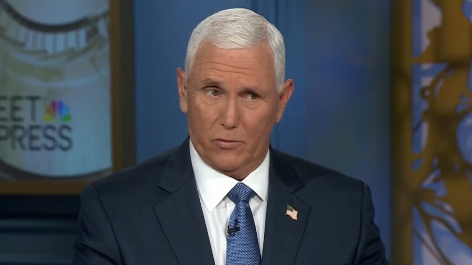 Mike Pence speaking during an interview on Meet the Press, wearing a suit and tie with an American flag pin.