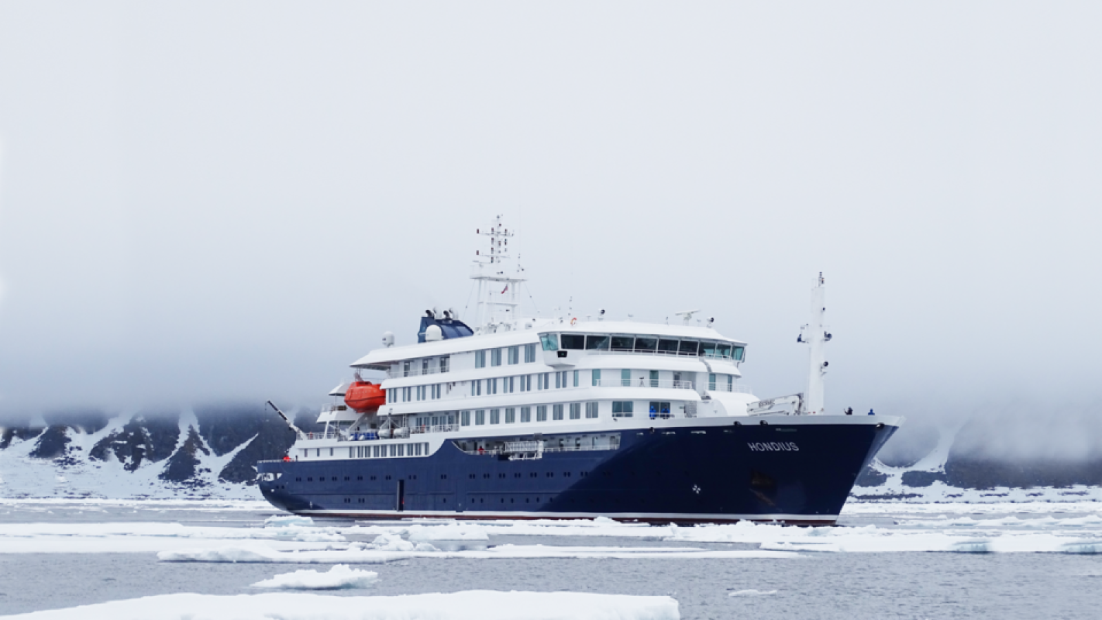 Expedition cruise ship navigating through icy waters in a remote Arctic landscape.