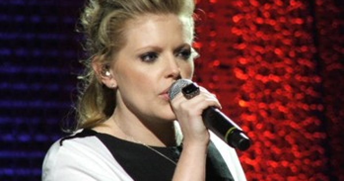 Singer performing on stage with a microphone, showcasing a dynamic live music atmosphere.
