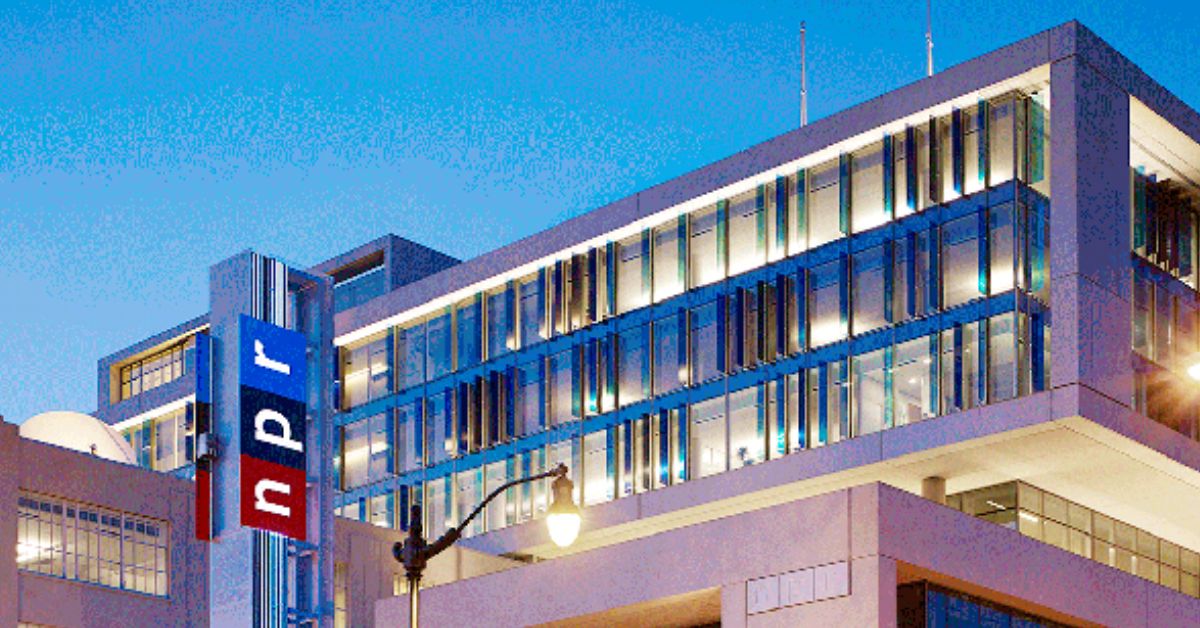 NPR headquarters building illuminated at dusk, showcasing modern architecture and the iconic NPR logo prominently displayed.