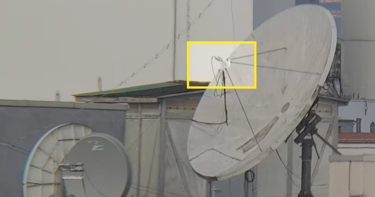 Satellite dish on a rooftop with visible cables and mounting equipment, showcasing urban telecommunications infrastructure.
